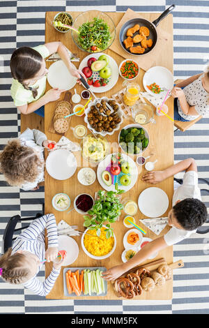 Vista dall'alto sui bambini mangiare sano la cena al tavolo durante la festa di compleanno Foto Stock