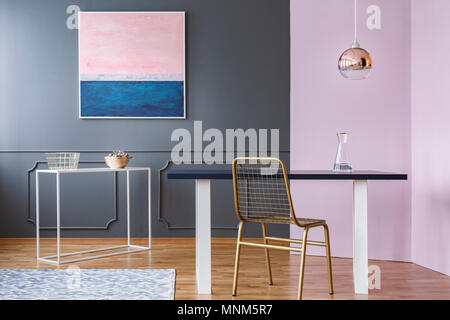 Sedia in oro a tavola sotto la lampada nella moderna sala da pranzo interni con colori rosa e blu dipinto Foto Stock