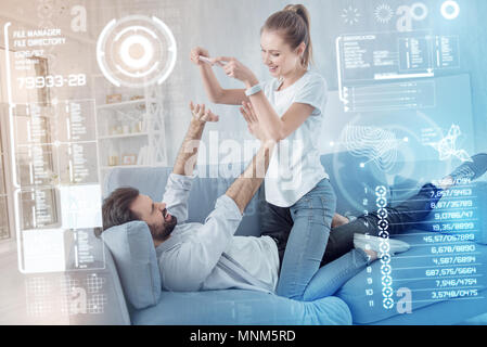 Giovane donna tenendo un smartphone e il suo fidanzato mettere le mani in alto Foto Stock