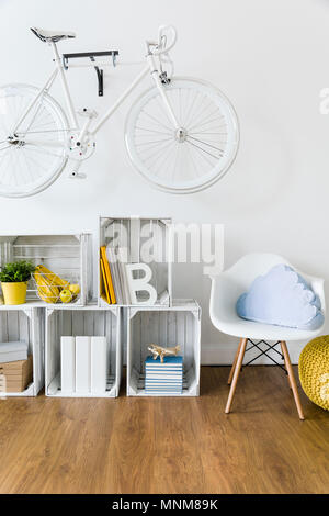 Legno, mobili fatti a mano e bicicletta appesa al muro in camera luminosa con pavimento Foto Stock