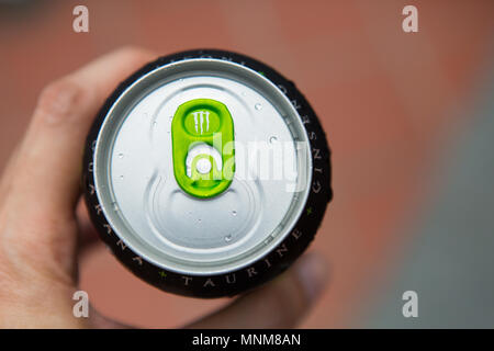 A tenere in mano una lattina di Monster Energy drink con un colore verde anello di trazione design Foto Stock