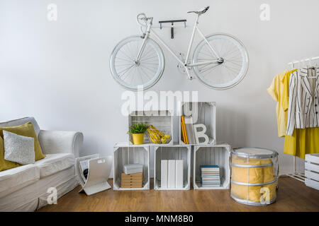 Moderno ed elegante lounge con ripiano di scatole di legno. White vintage bicicletta appesa sul muro Foto Stock