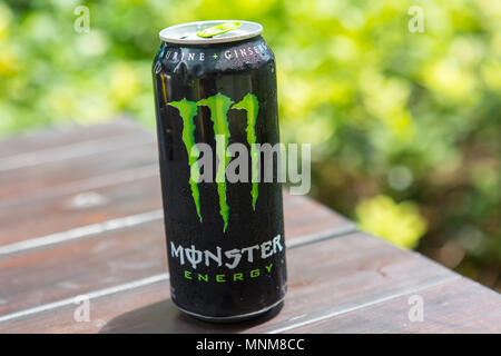 Monster Energy drink sul tavolo su sfondo verde. Foto Stock