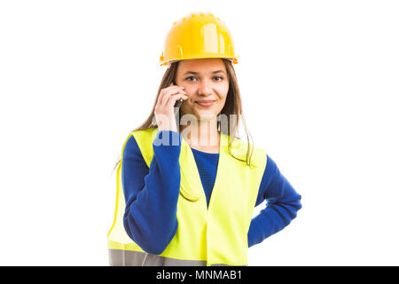 Giovane donna attraente un architetto o un ingegnere utilizza lo smartphone per chiamate professionali come dispositivo di comunicazione concetto isolato su sfondo bianco Foto Stock