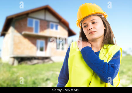 Giovani donne ingegnere o architetto avente dolore alla spalla come esaurito stanco lavoratore concetto su casa sfondo all'aperto Foto Stock