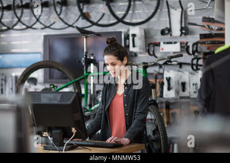 Titolare di una piccola azienda di usare il computer in un negozio Foto Stock