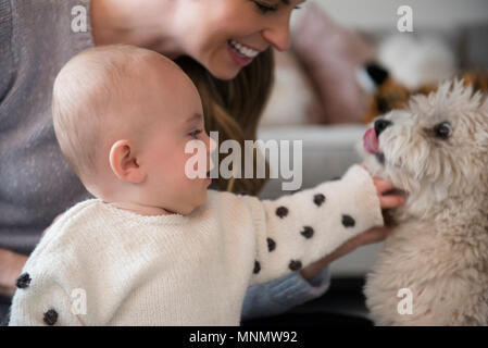 Il bambino e la madre figlia (18-23 mesi) giocando con il cane Foto Stock