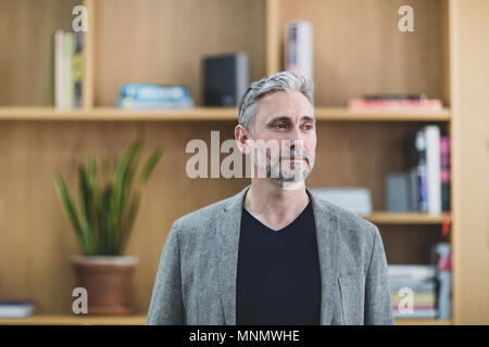 Imprenditore a guardare fuori dalla finestra pensando Foto Stock