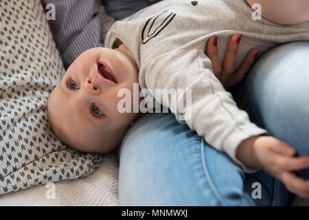Baby girl (12-17 mesi) sdraiato sulla mamma lap Foto Stock