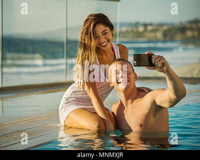 Giovane tenendo selfie in piscina Foto Stock