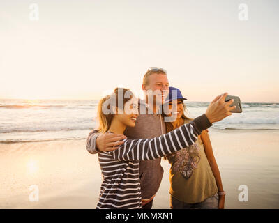 Famiglia tenendo selfie sulla spiaggia Foto Stock