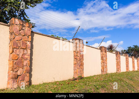 Elettrificate recinto di filo sul lungo muro di cinta della sicurezza per cancelli di proprietà residenziale. Foto Stock