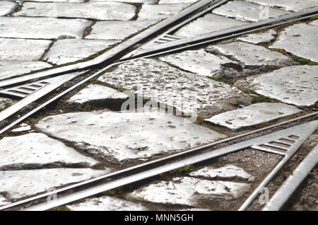 Primo piano di metallo binari del treno incorporato in una vecchia strada acciottolata a Palermo, Sicilia, Italia Foto Stock