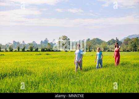 La famiglia di madre e due bambini godendo tranquilla passeggiata in campi di riso con viste mozzafiato sulle montagne in Sri Lanka Foto Stock