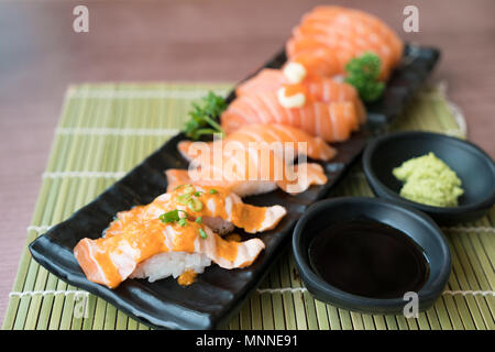 Misto sushi di salmone sulla piastra nera lungo con salsa giapponese e foglia verde decorazione, il cibo Giapponese, vicino fino al sushi . Foto Stock