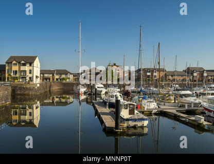 Yacht e Barche a motore ormeggiata in Penarth Marina, Cardiff, Galles, in inizio di mattina di luce, con riflessioni ancora in acqua Foto Stock