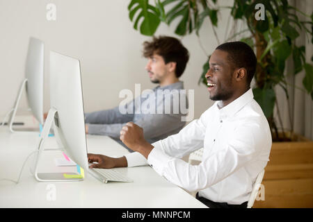 Felice dipendente nero eccitato da vincere online o un buon risultato Foto Stock