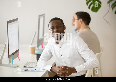 Happy businessman africani guardando la telecamera seduti al posto di lavoro Foto Stock