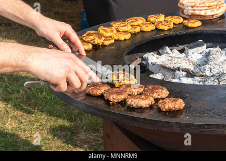 Street per la cottura di alimenti, rendendo la carne e hamburger vegetali, il dettaglio closeup immagine dello chef mani, lo chef trasforma gli hamburger in un caldo barbecue. Demo Foto Stock