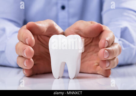 Mano d'uomo proteggere igienicamente sano Dente Bianco sul tavolo riflettente Foto Stock