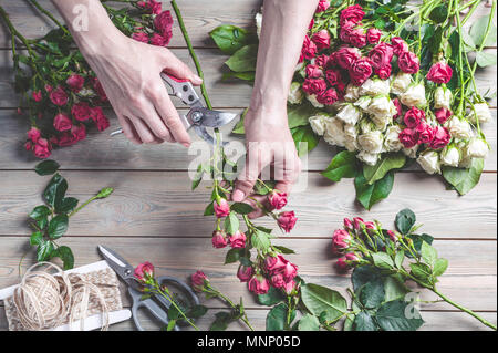 Fioraio al lavoro. Mani femminili raccogliere un matrimonio bouquet di rose. Le persone nel processo di lavoro Foto Stock