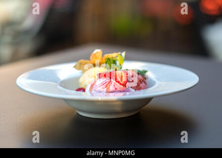 Il gelato servito in una piastra con le fragole e foglie di menta Foto Stock