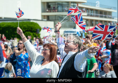 Persone allietare e wave Union Jack Flag come si guarda il principe Harry e Meghan Markle wedding su un grande schermo in un Royal Wedding evento a Bexhill sul mare in East Sussex, Inghilterra. Foto Stock