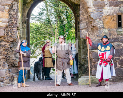 Dirleton, East Lothian, Scozia, Regno Unito, 19 maggio 2018. Dirleton Castle attack rievocazione. Il centro storico si intraversa società allestimento di un ironico rievocazione di un attacco da parte di Robert the Bruce, re di Scozia, intorno al 1311, a prendere il castello dall'inglese, vestito in abiti autentici e corazza ed armato con armi di replica in ambienti storici della Scozia Dirleton Castle. Gli uomini che giocano i soldati in costume, indossando il bollitore helms e portante i lucci. Un uomo con un drago gallese simbolo sul suo costume Foto Stock