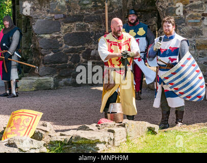 Dirleton, East Lothian, Scozia, Regno Unito, 19 maggio 2018. Dirleton Castle attack rievocazione. Il centro storico si intraversa società allestimento di un ironico rievocazione di un attacco da parte di Robert the Bruce, re di Scozia, intorno al 1311, a prendere il castello dall'inglese, vestito in abiti autentici e corazza e brandendo armi replica, inclusi i lucci, in ambiente storico della Scozia Dirleton Castle. Gli uomini che giocano di Robert the Bruce e Aymer de Valence, 2° Conte di Pembroke Foto Stock