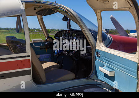 Il piano Piper Cherokee sorge sull'erba verde in una giornata di sole. Una piccola aviosuperficie privata con piani diversi. Aviazione privata Foto Stock