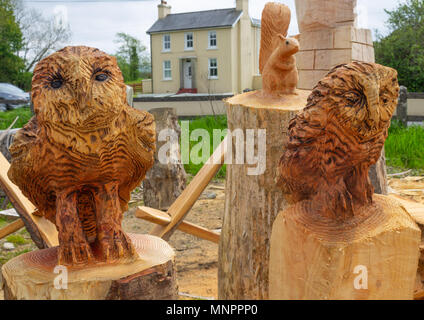 Intaglio del legno di una coppia di gufi tagliati da un solido pezzo di tronco di albero in un intagliatori del legno in cantiere drimoleague, Irlanda. Foto Stock