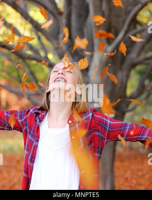 Di Yakima, Washington / STATI UNITI D'America - 7 Novembre 2016: giovane ragazza carina con bretelle getta le foglie di autunno in aria in corrispondenza della zona di Yakima Arboretum di Washington. Foto Stock