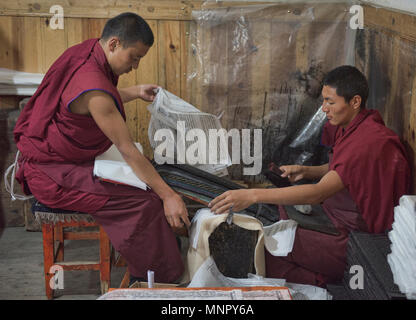 I monaci rendendo la carta a mano scritture e stampe di woodblock all'interno della sacra Scrittura Bakong Stampa Monastero a Dege, Sichuan, in Cina Foto Stock