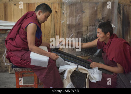 I monaci rendendo la carta a mano scritture e stampe di woodblock all'interno della sacra Scrittura Bakong Stampa Monastero a Dege, Sichuan, in Cina Foto Stock