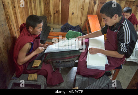 I monaci rendendo la carta a mano scritture e stampe di woodblock all'interno della sacra Scrittura Bakong Stampa Monastero a Dege, Sichuan, in Cina Foto Stock