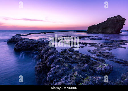 Tramonto Luminosa brilla su morbido piscine di acqua con piccole cascate.Un gigante di roccia in background.mare Mediterraneo, Israele Foto Stock