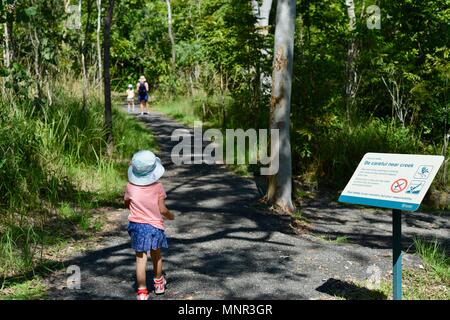 Una madre e bambini a piedi lungo un sentiero in una foresta, Jourama cade, Bruce Hwy, Yuruga QLD, Australia Foto Stock