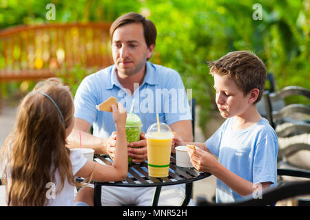 Giovane padre e i suoi due bambini in outdoor cafe sul giorno di estate Foto Stock