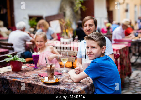 Il padre e i suoi bambini a outdoor cafe sul giorno di estate Foto Stock