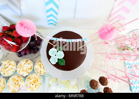 Bacche, popcorn, tartine, caramelle e una torta al cioccolato su un tavolo da dessert a parte Foto Stock