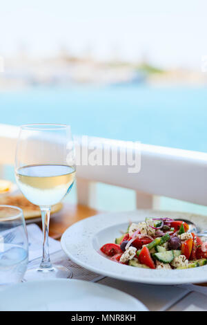 Freschi e deliziosi insalata greca e bicchiere di vino bianco per il pranzo al ristorante all'aperto Foto Stock