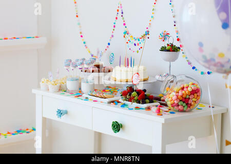 Torta, caramelle, marshmallows, cakepops, frutta e altri dolci sulla tavola da dessert a kids festa di compleanno Foto Stock