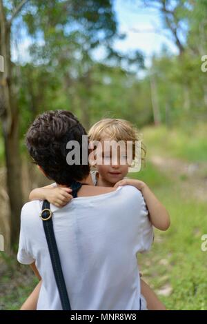 Una madre che porta la figlia attraverso una foresta, Rollingstone QLD, Australia Foto Stock