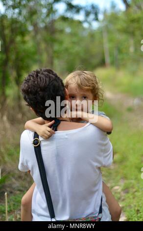 Una madre che porta la figlia attraverso una foresta, Rollingstone QLD, Australia Foto Stock