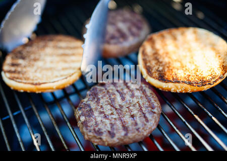 La cottura alla griglia di carni bun e burger costolette di carne per hamburger fatti in casa per la cottura all'aperto sul giorno di estate Foto Stock