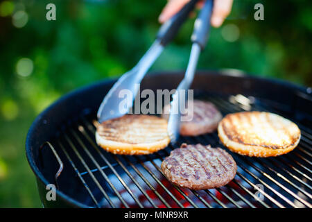 La cottura alla griglia di carni bun e burger costolette di carne per hamburger fatti in casa per la cottura all'aperto sul giorno di estate Foto Stock