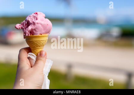 Close up donna mano azienda freschi cono di cialda con gelato al lampone Foto Stock