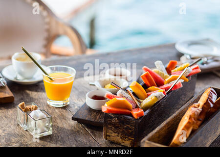 Close up di deliziosi cibi biologici serviti per colazione sulla tavola in legno rustico. Frutta, succhi di frutta, pane e marmellata. Foto Stock