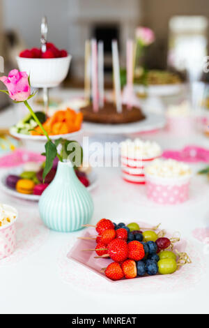 Torta, caramelle, marshmallows, popcorn, frutta e altri dolci sulla tavola da dessert a kids festa di compleanno Foto Stock