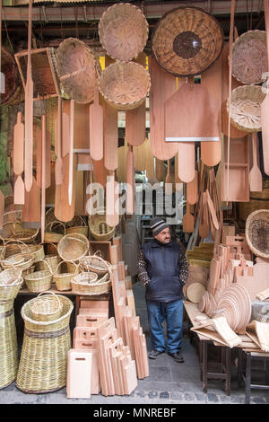 Maschio adulto merchant sta con le mani in tasca in ingresso al negozio che vende articoli in legno e tessuto cesti, Istanbul, Turchia. Foto Stock